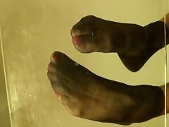 Soles arches view in black nylon socks, pink toes and one na